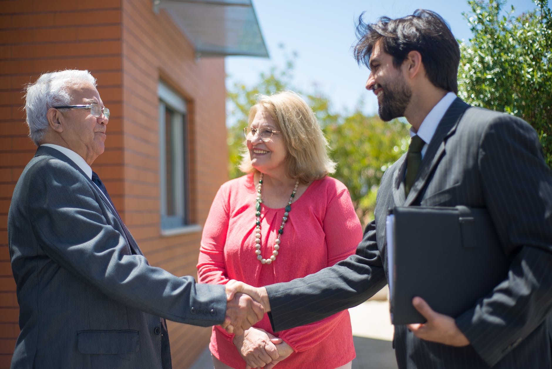 man in a suit with a briefcase shaking hands with a couple